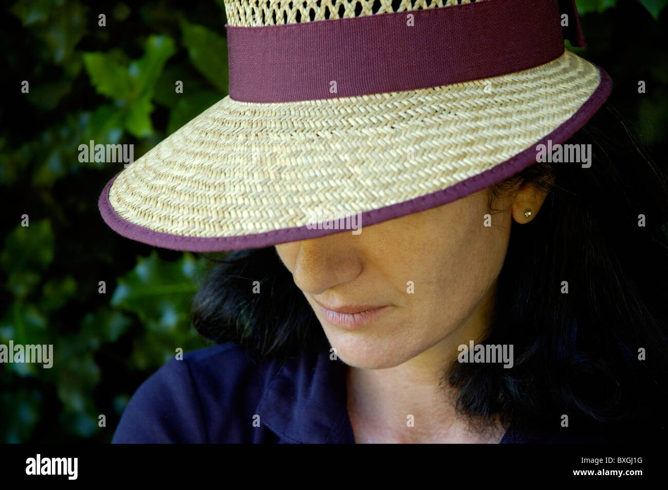 Portrait of a woman wearing a straw hat and looking sad. Stock Photo