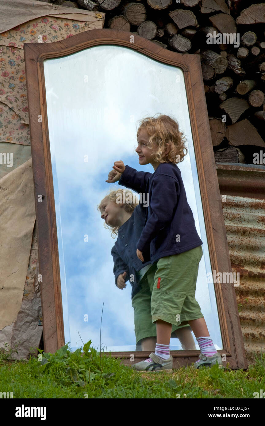 Four year old girl having fun playing around with her reflection in a large mirror. Stock Photo