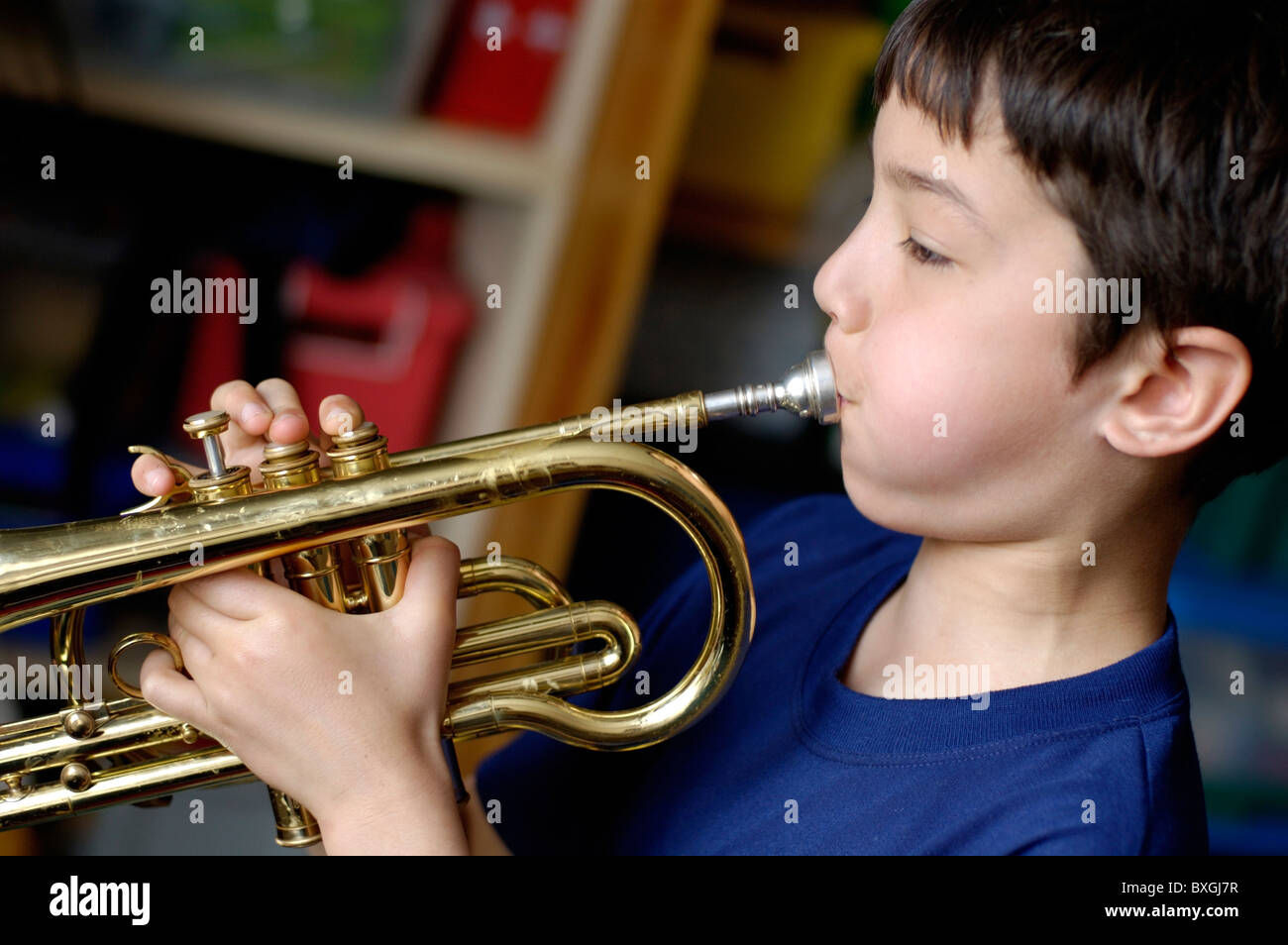 Boy breathing into a trumpet as he practices in his bedroom. Stock Photo