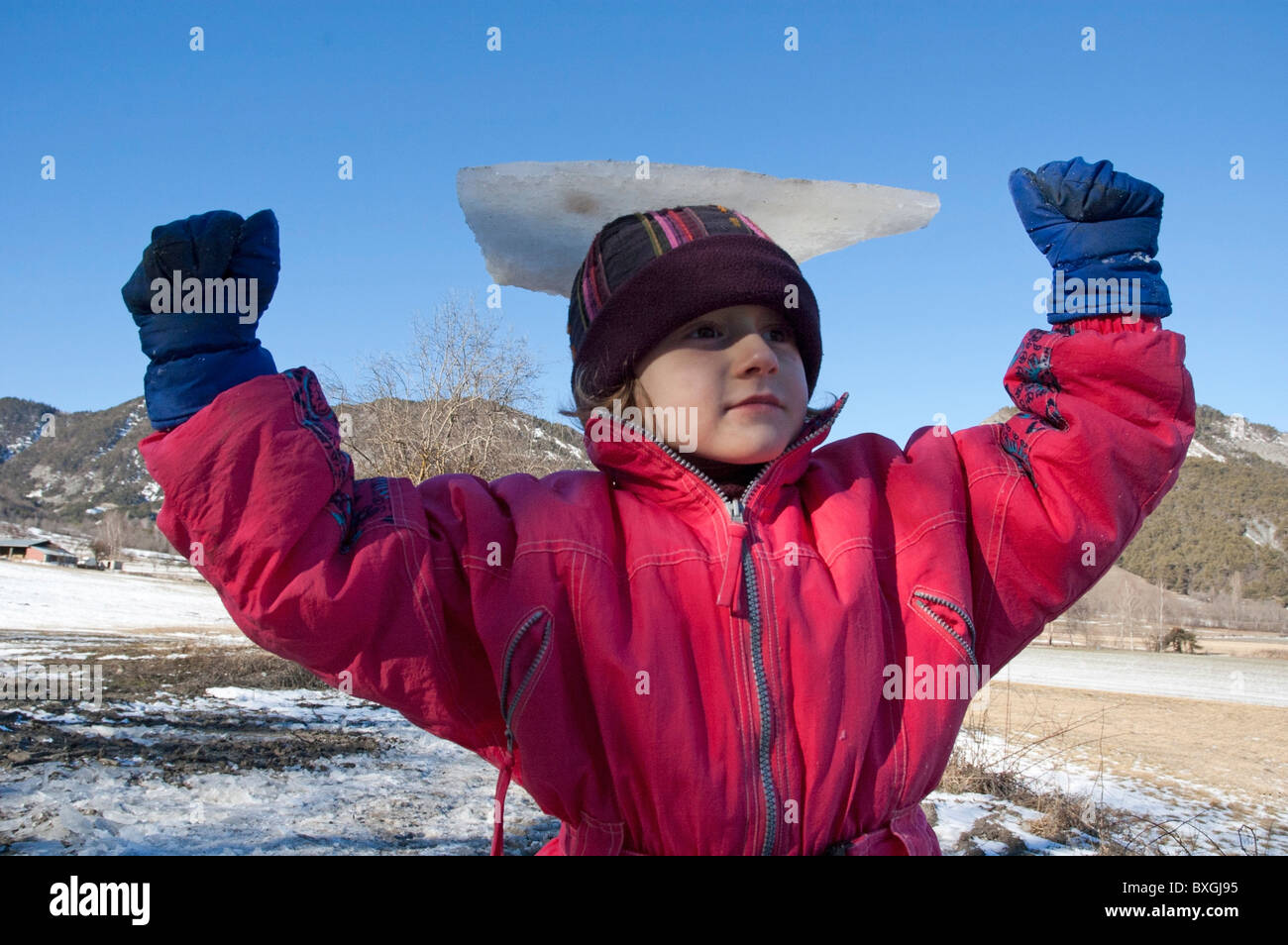 Young girl balancing a piece of ice on her head as a trophy. Stock Photo