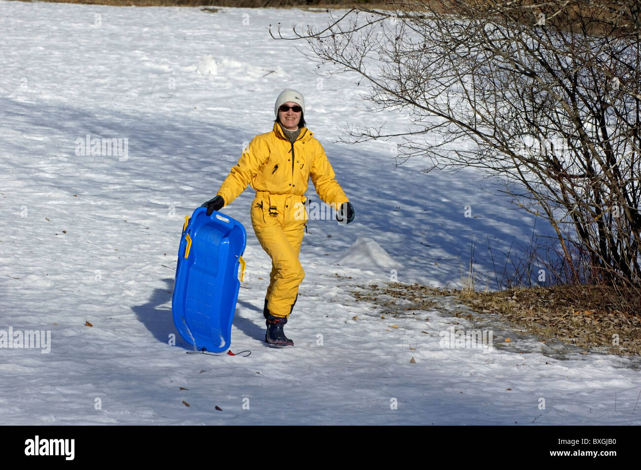 Woman carrying a sled along in the snow. Stock Photo