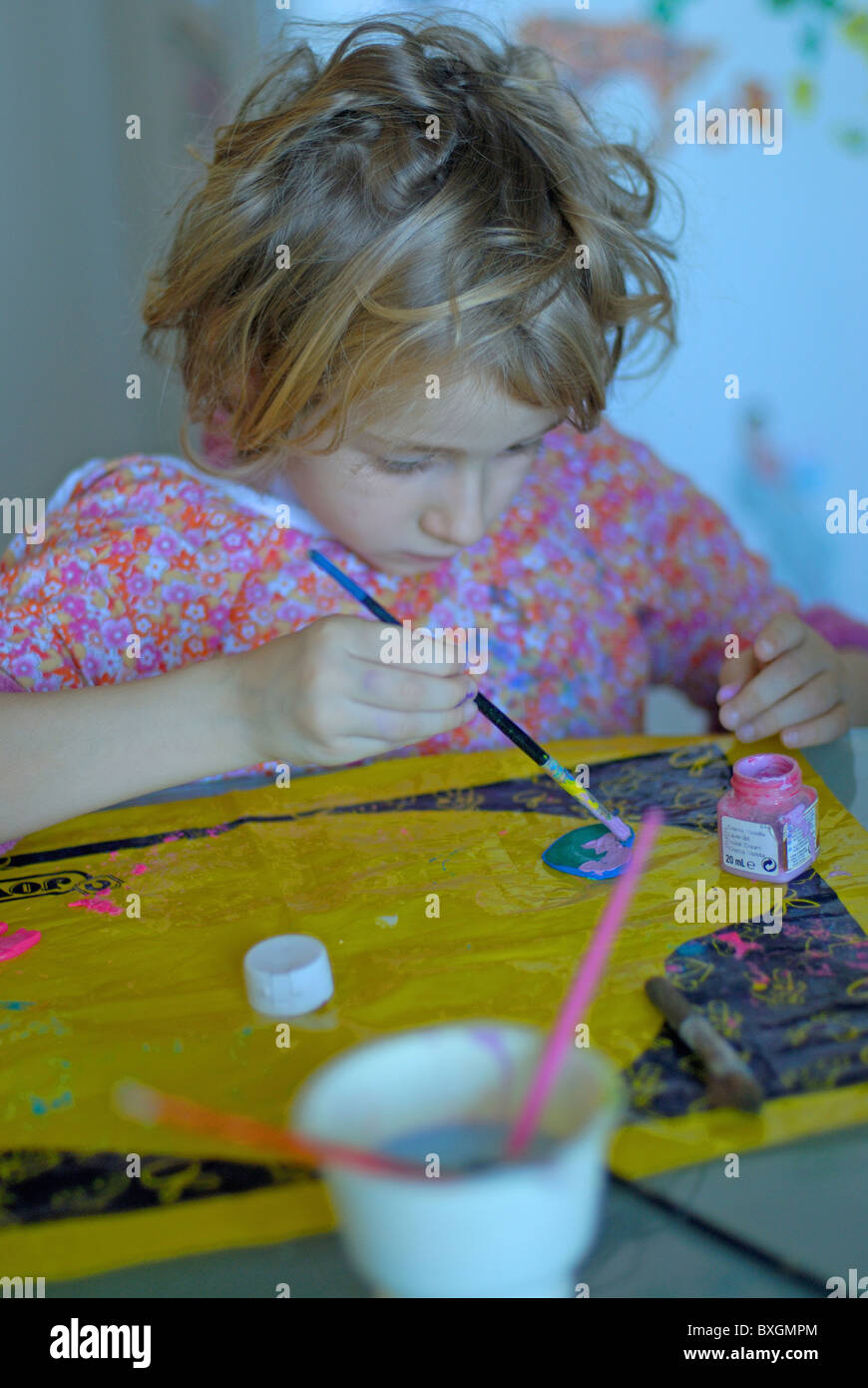 Little blond girl painting in the kitchen, France. Stock Photo