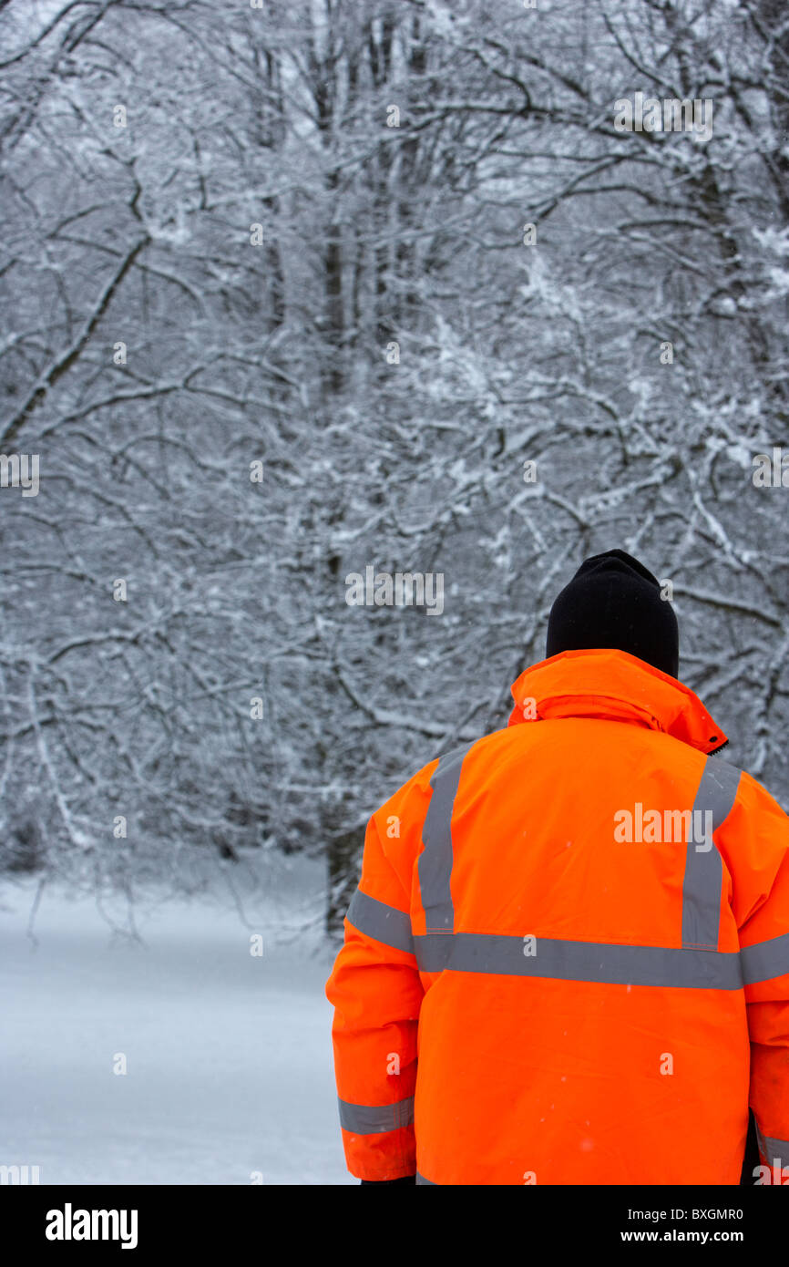 man wearing hivis orange jacket on a cold snowy winters day Belfast Northern Ireland Stock Photo