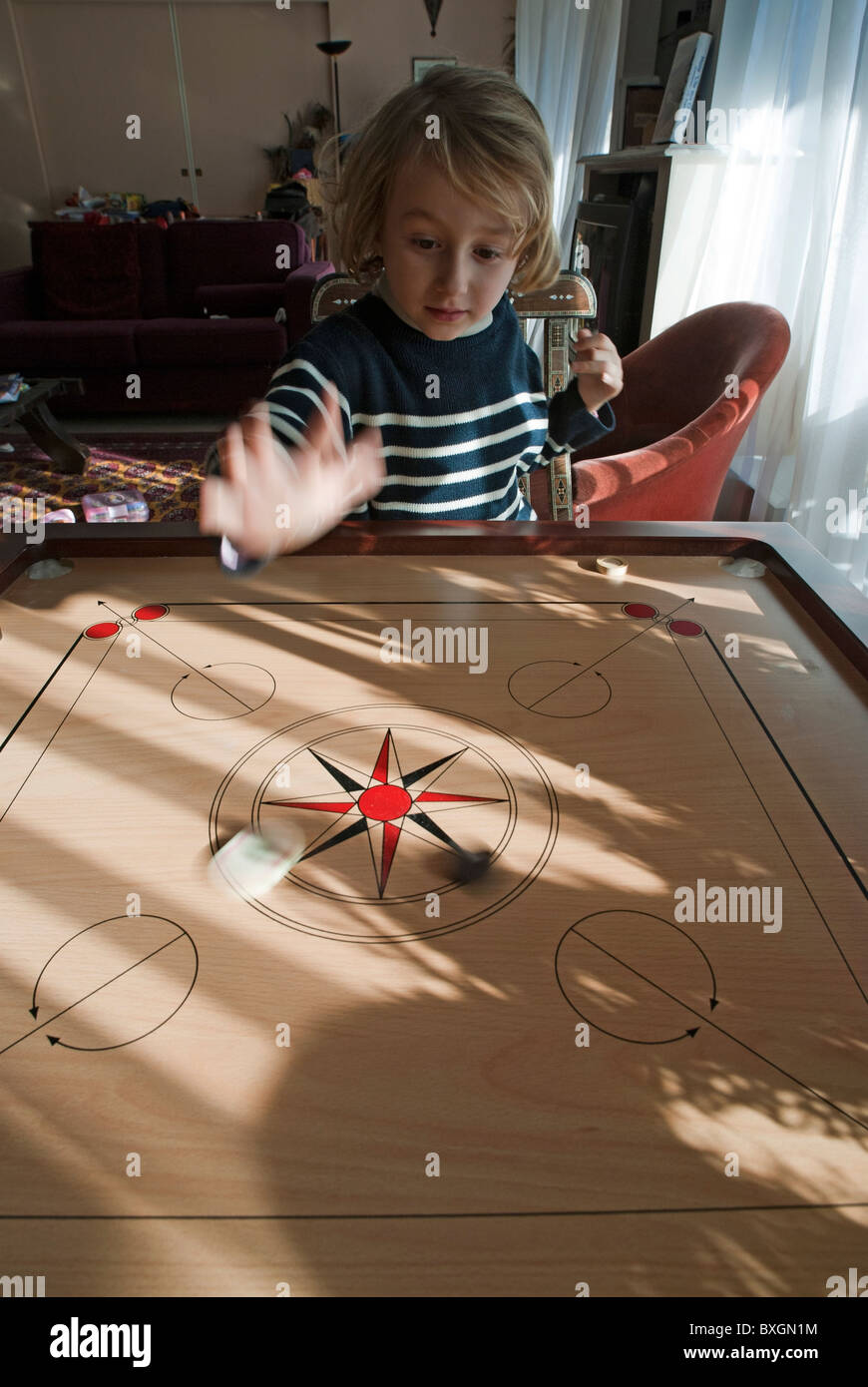 Little blond girl playing Carrom, the Indian board game, France. Stock Photo
