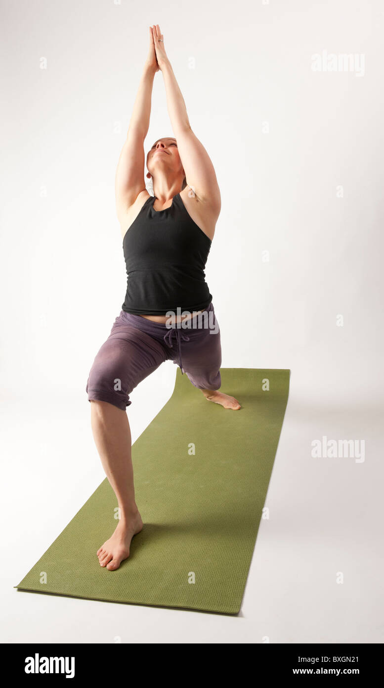 A young woman doing yoga on a green mat Stock Photo - Alamy