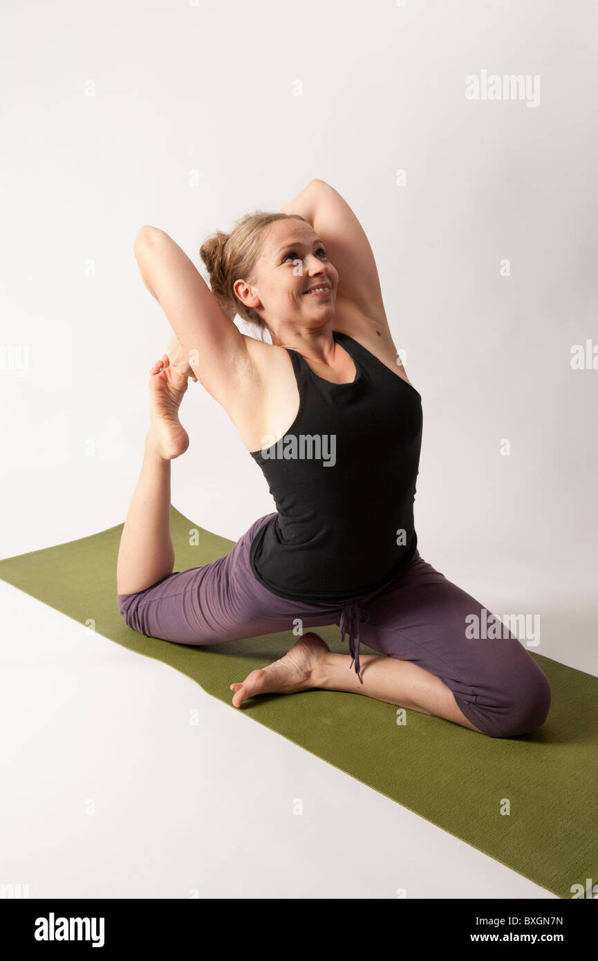 A young woman doing yoga on a green mat Stock Photo - Alamy