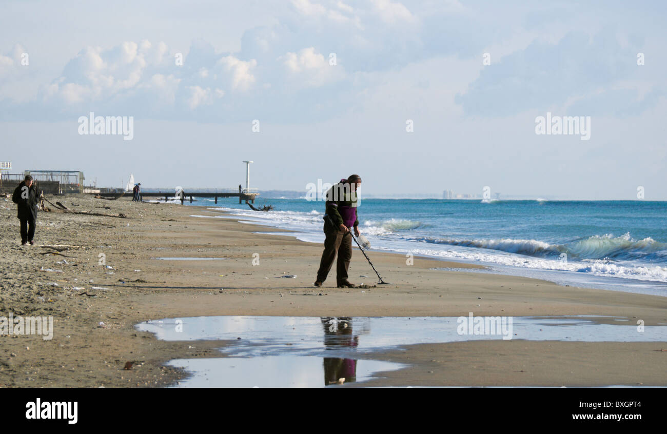 Ostia beach, man with metal detector searching valuables. Others passerbies in the picture too. Stock Photo