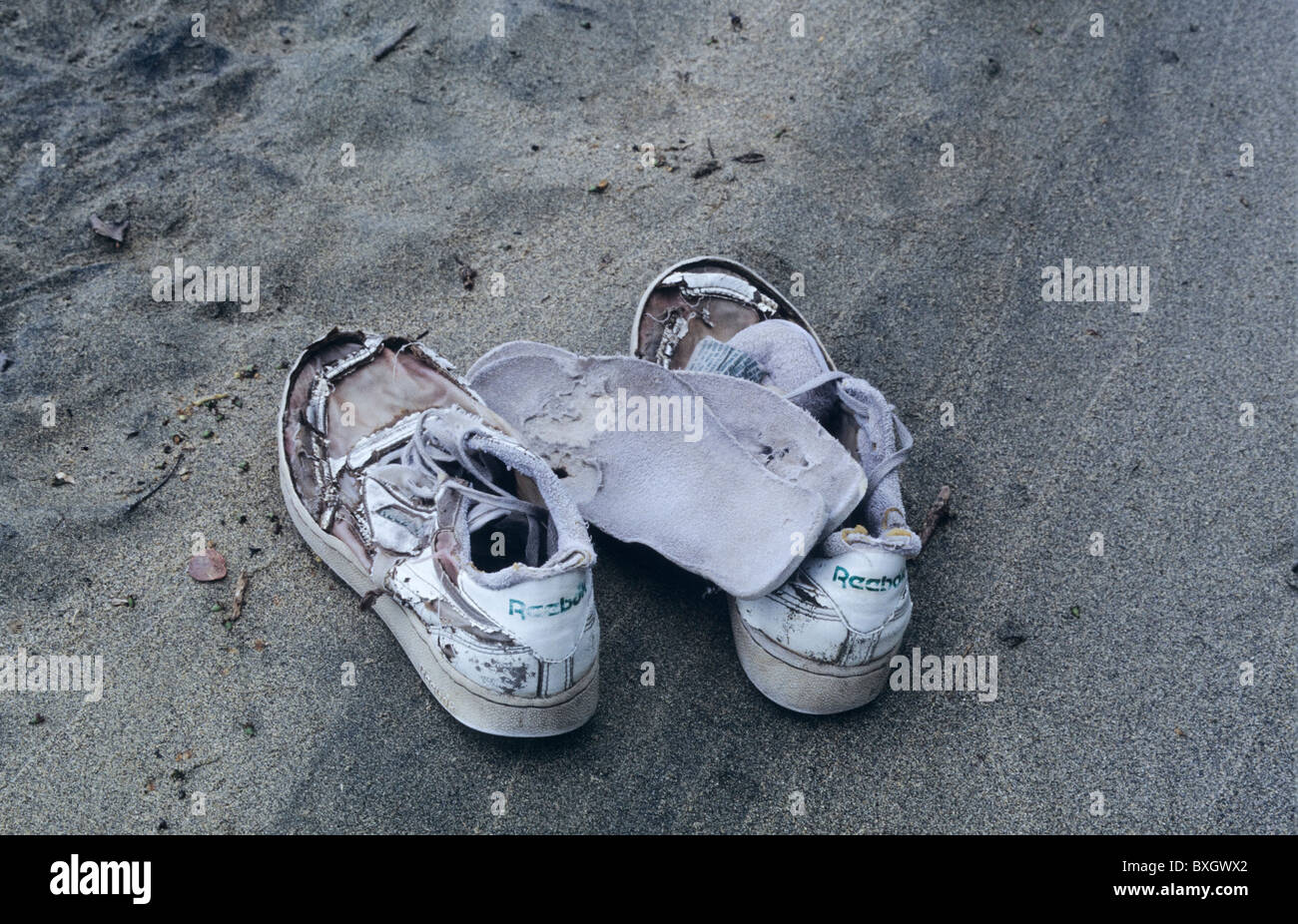 Costa Rica, rotten reebock Sneakers, worn, removed insoles, grey sand Stock Photo