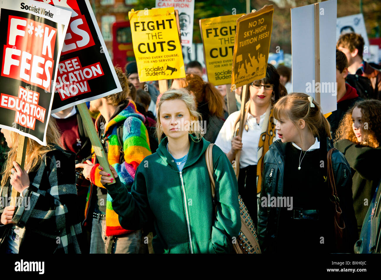 student girl stands alone with fight the cuts placard amidst more young students on anti-cuts demonstration march 2010, brighton Stock Photo
