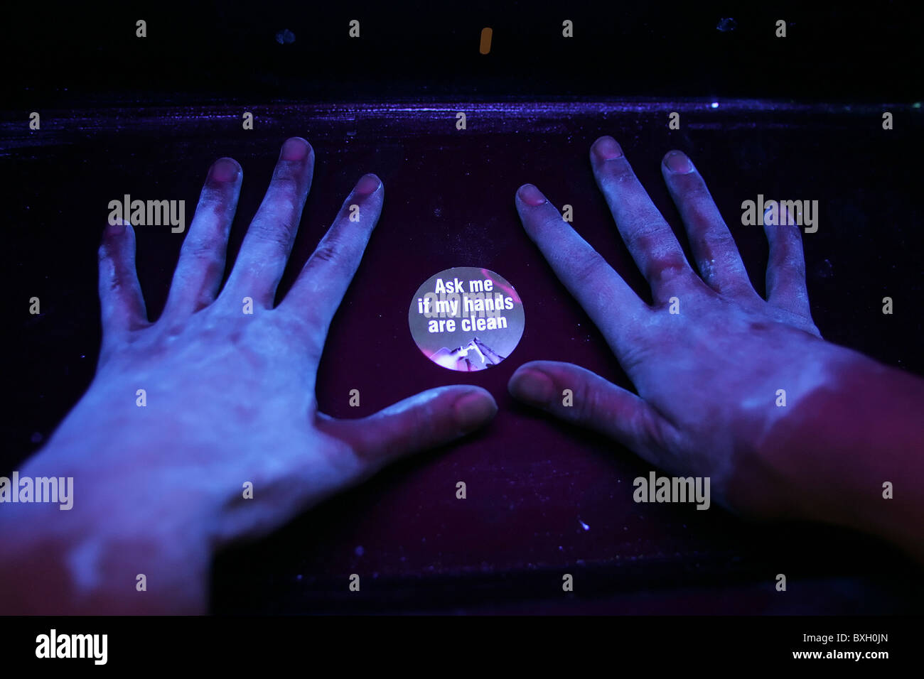 Hands placed under a UV light source indicate how effective normal hand-washing has been. Stock Photo