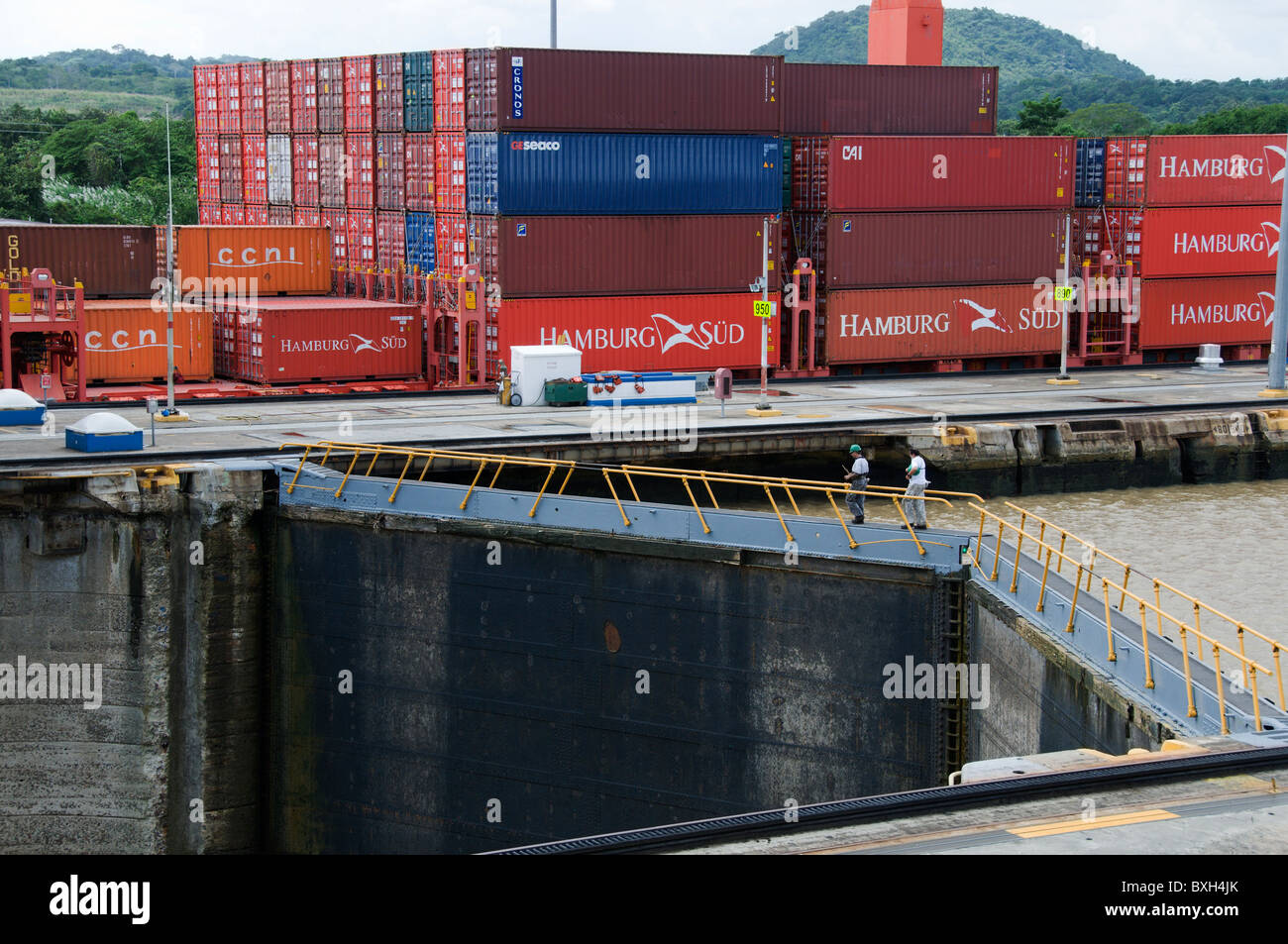 A fully loaded cargo ship filled with containers moves through the Miraflores Locks in the Panama Canal. Stock Photo