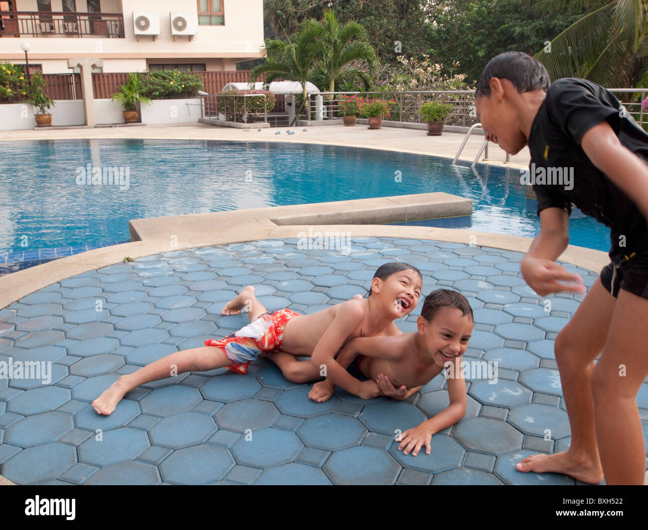 Boys playing wrestling at a swimming pool Stock Photo