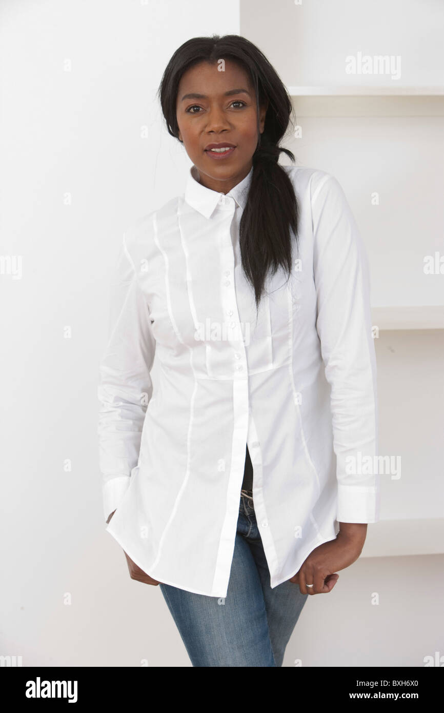 Afro Caribbean woman with long straightened hair in white shirt and jeans cropped at mid thigh Stock Photo