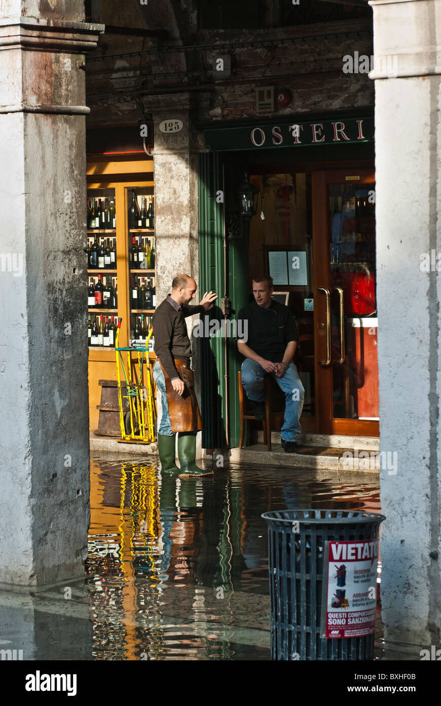 People having a break on a street flooded by 'acqua alta', Venice, Italy, Europe Stock Photo