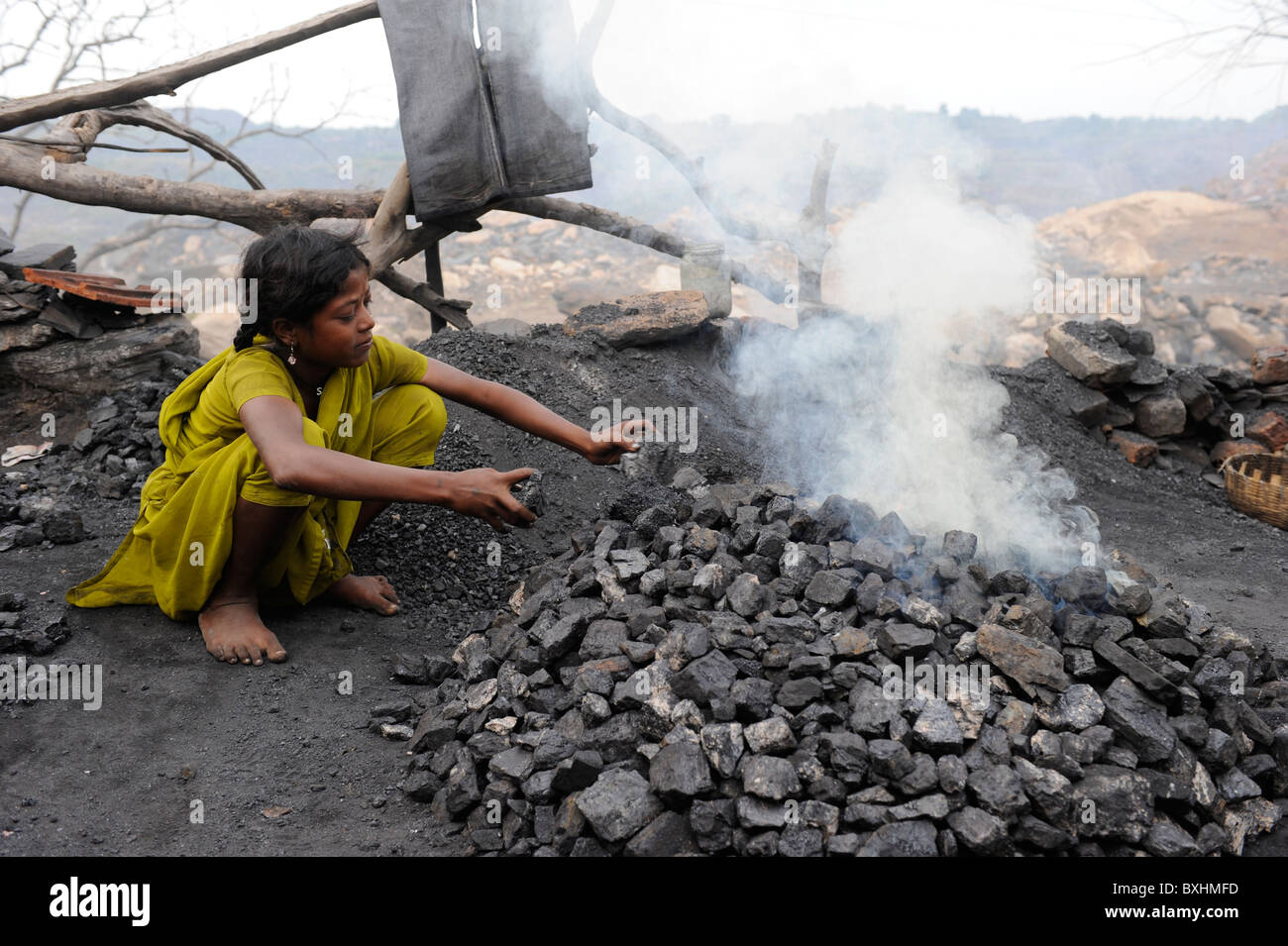 India Jharkhand Jharia children collect and burn coal from coalfields , behind burning coalfields of BCCL Ltd. Stock Photo