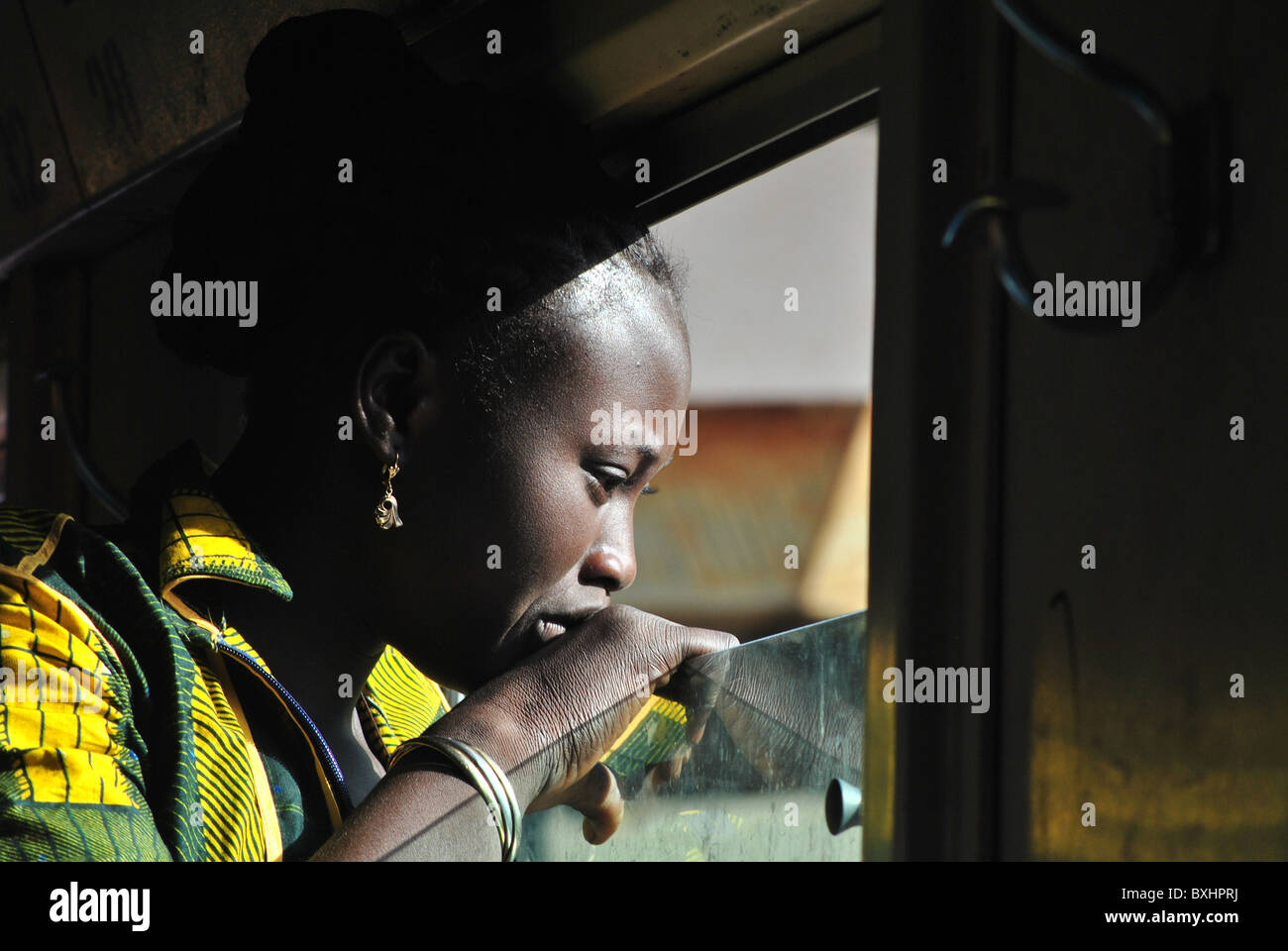 Girl looking out of a train window while traveling from Burkina Faso to Abidjan Stock Photo