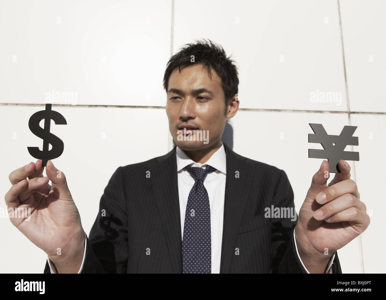 Businessman holding yen sign and dollar sign Stock Photo - Alamy