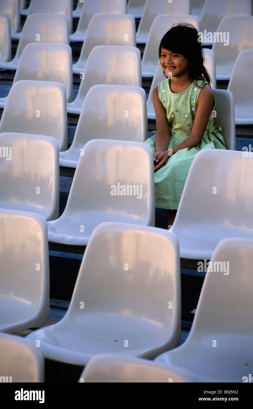 Smiling young girl seated alone among unoccupied seats, France. Stock Photo