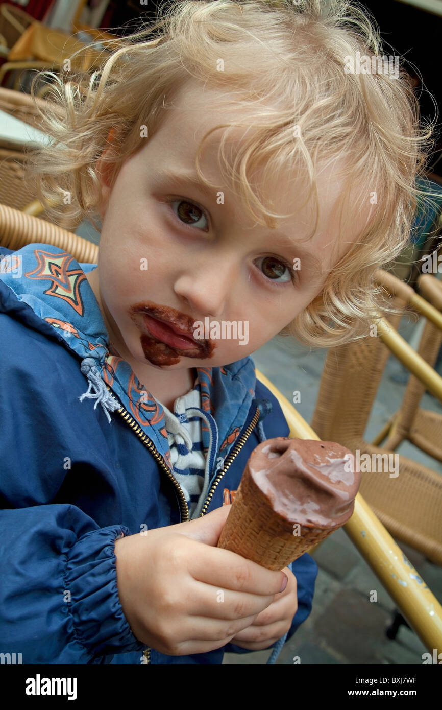Little girl eating a chocolate ice cream cone and getting most of it on her face, Paris, France. Stock Photo