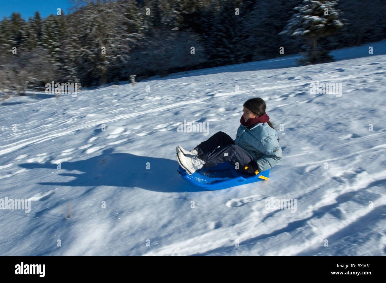 Young girl sledding down a snowy hill. Stock Photo