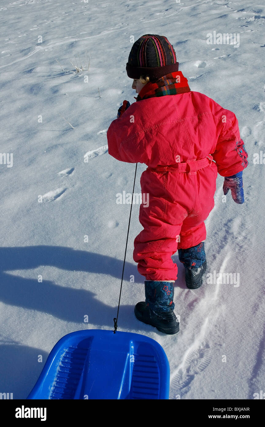 Young girl towing a sled along in the snow. Stock Photo