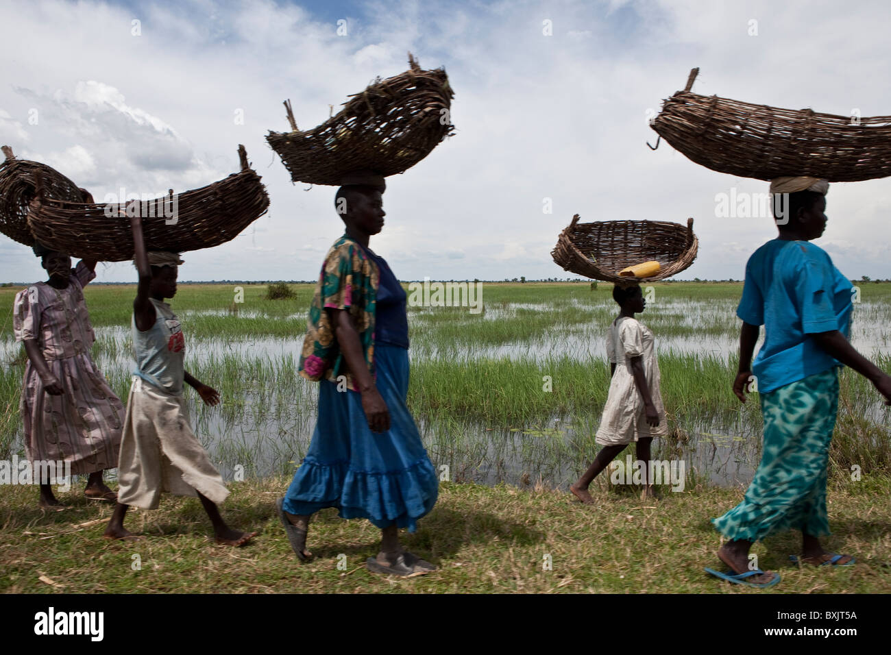 Women walk with baskets on their heads along the shores of Lake Kyoga, near Soroti, in Uganda, East Africa. Stock Photo