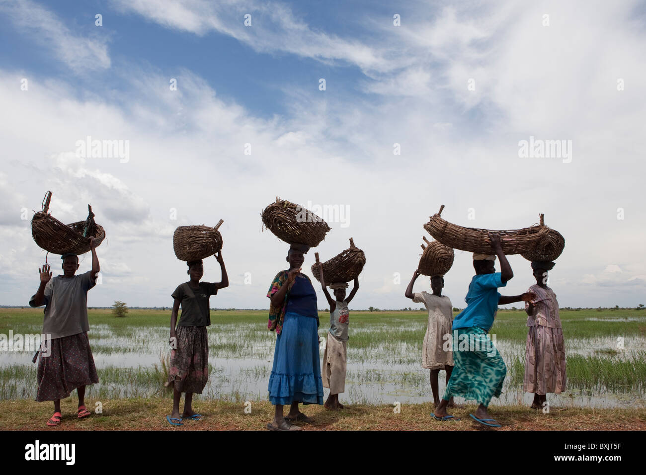 Women walk with baskets on their heads along the shores of Lake Kyoga, near Soroti, in Uganda, East Africa. Stock Photo