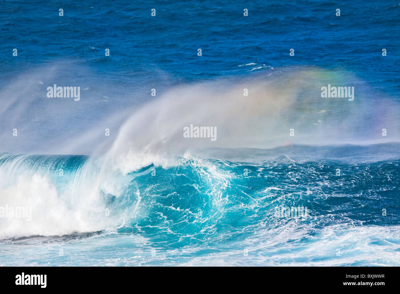 Huge breaking wave with a nice tube and a rainbow in the spray. Stock Photo