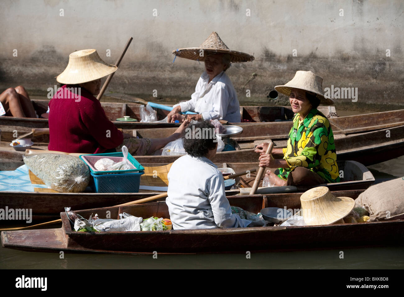 Old ladies take a break from selling food, congregate and share gossip through the Damnoen Saduak floating market. Stock Photo