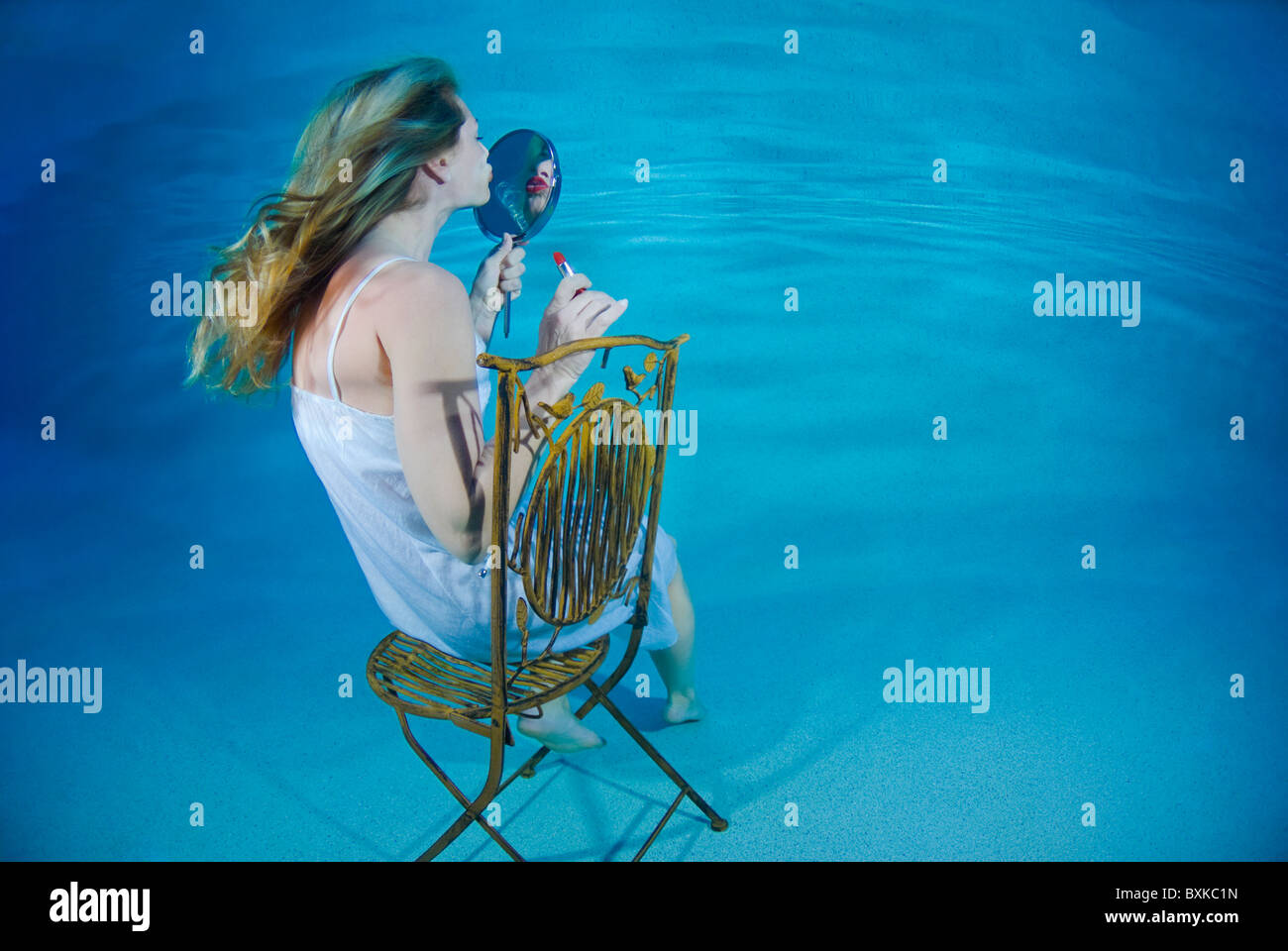 Woman Sitting On A Chair And Looking In The Mirror Underwater Stock