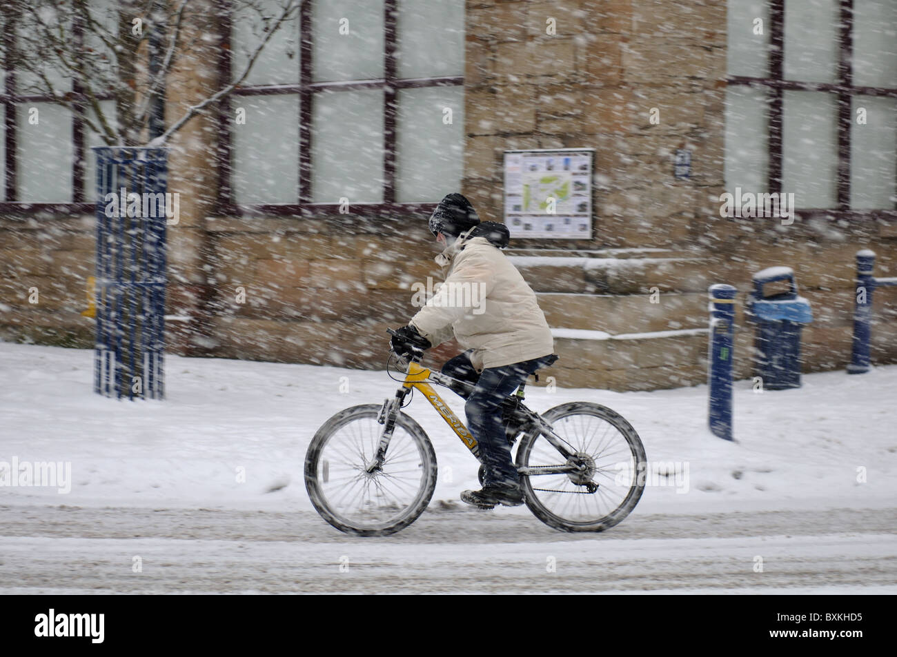 Cyclist riding during heavy snowfall, Warwick town centre, UK Stock Photo