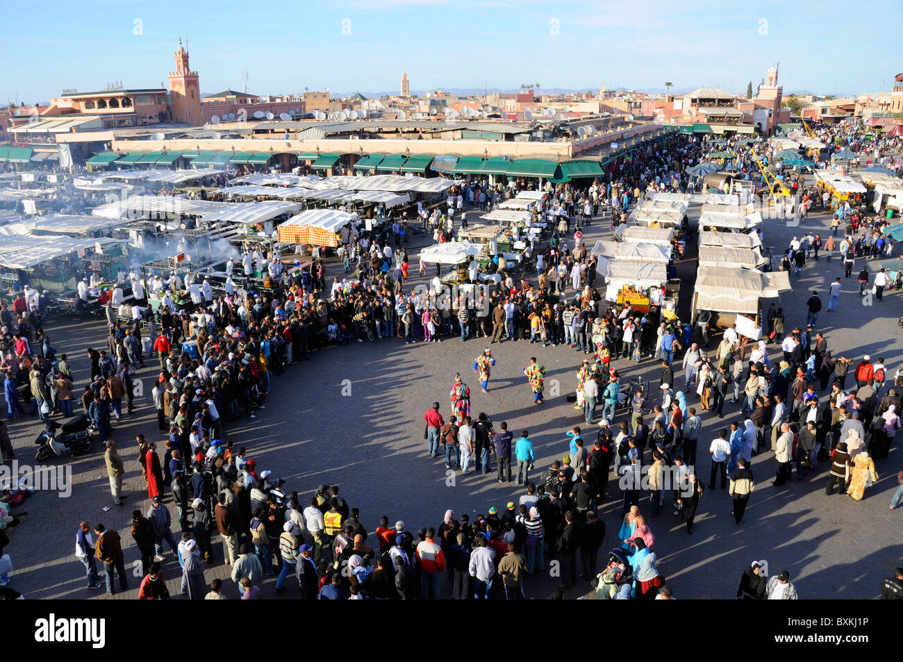 View onto Djemaa el-Fna meeting place with performance with crowd gathered Stock Photo