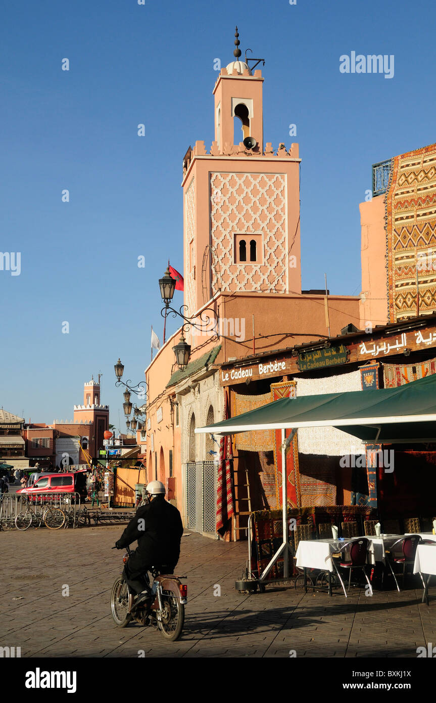 Street scene with mosque and man on moped at busy Djemaa el-Fna meeting Place in Marrakech Stock Photo