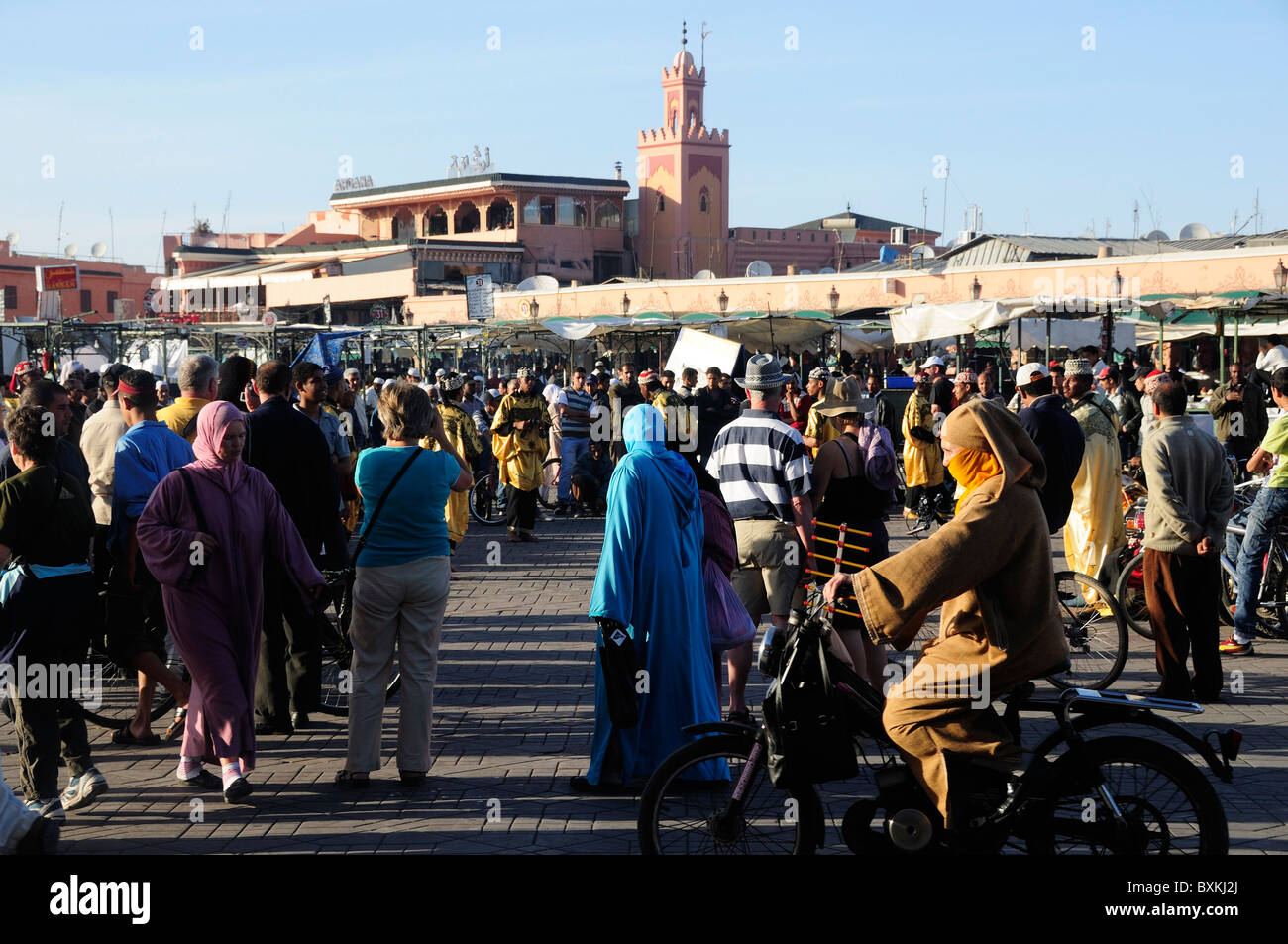 Crowds and street life at busy Djemaa el-Fna meeting place in Marrakech Minaret of Mosque Stock Photo