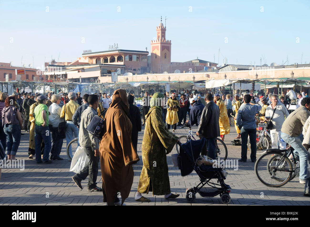 Crowds & street life at busy Djemaa el-Fna meeting place in Marrakech  Minaret of Mosque Stock Photo