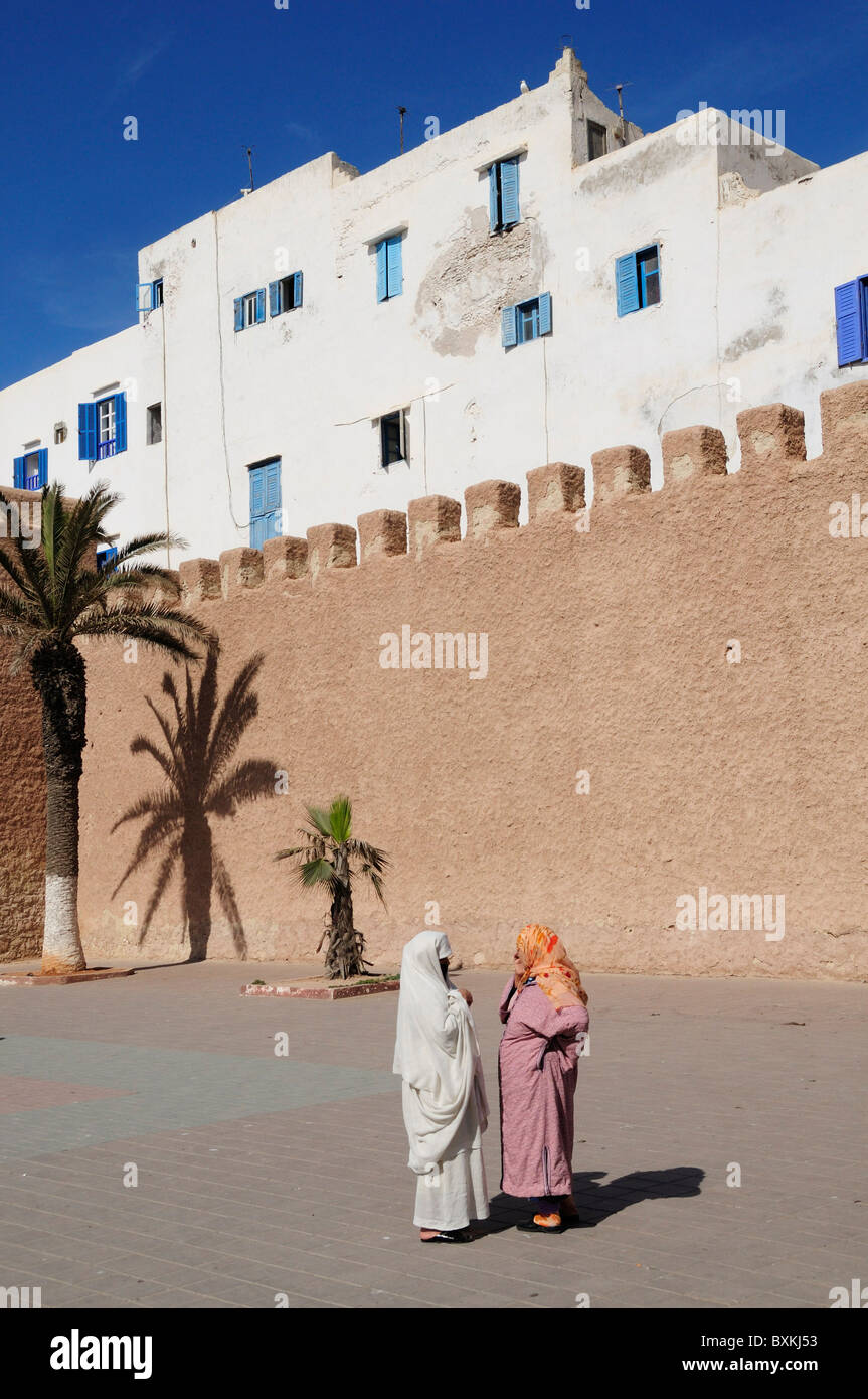 Women chatting beside town walls, Ave Okba Nafia Stock Photo