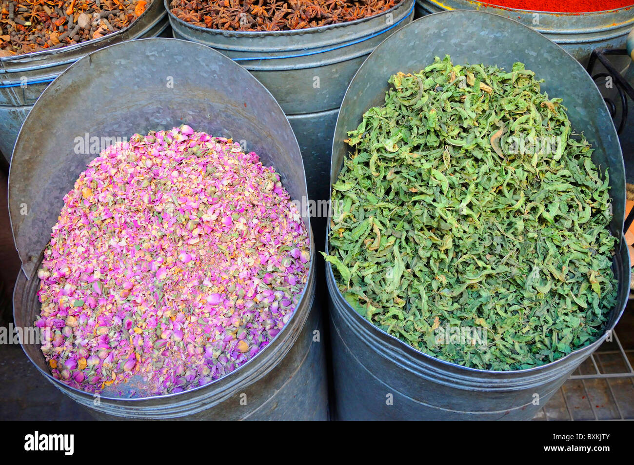 Dried roses and herbs in metal drums for sale in North Medina market in Marrakech Stock Photo