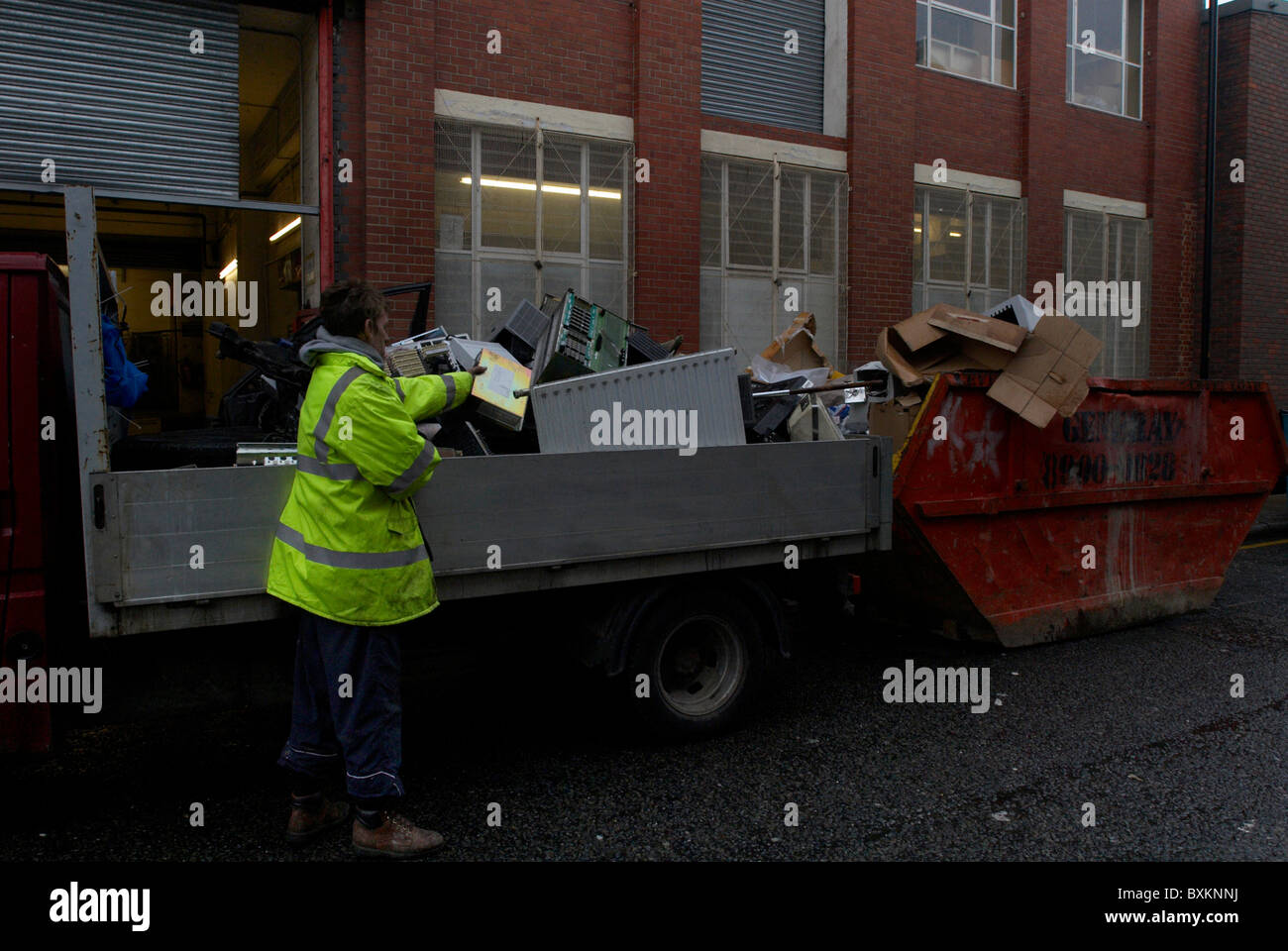 Scrap metal collectors searching through old office equipment in a skip