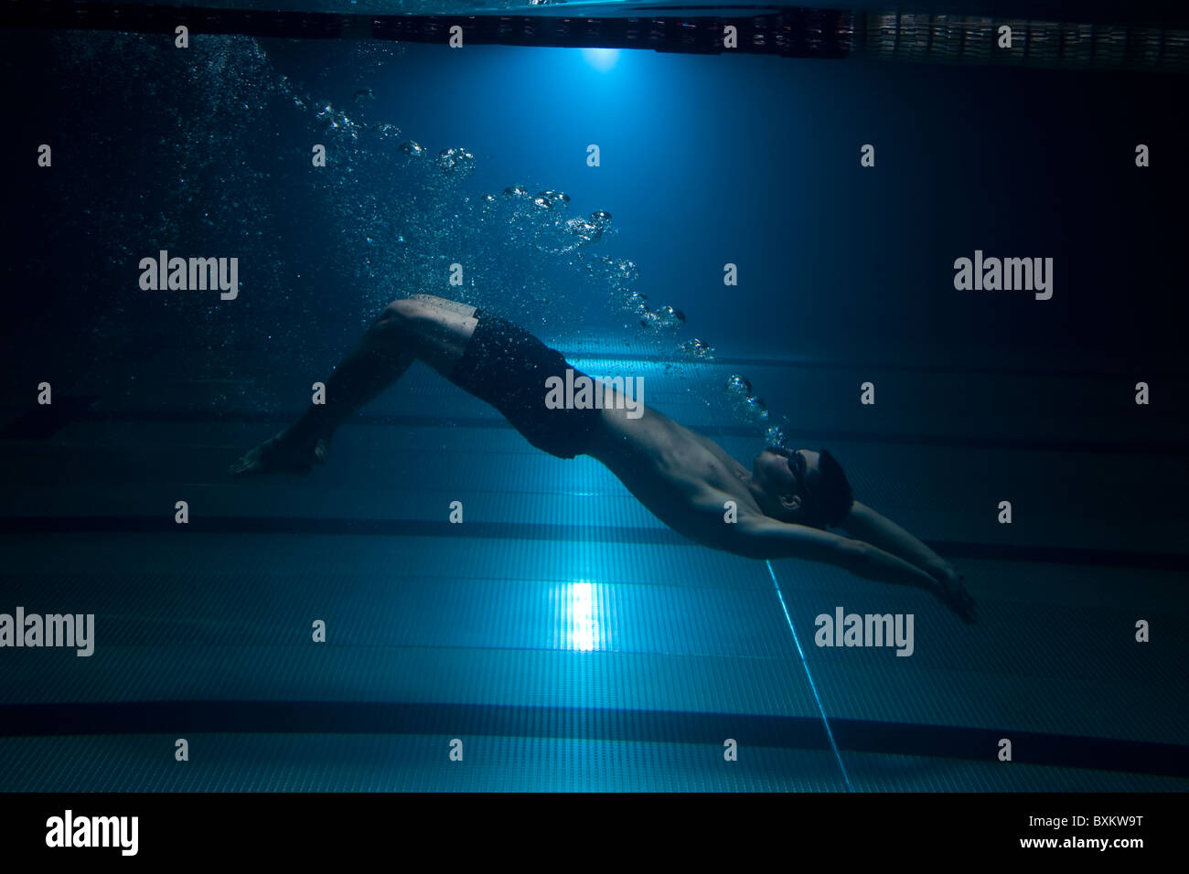 Swimmer swimming underwater exhaling bubbles on blue background Stock