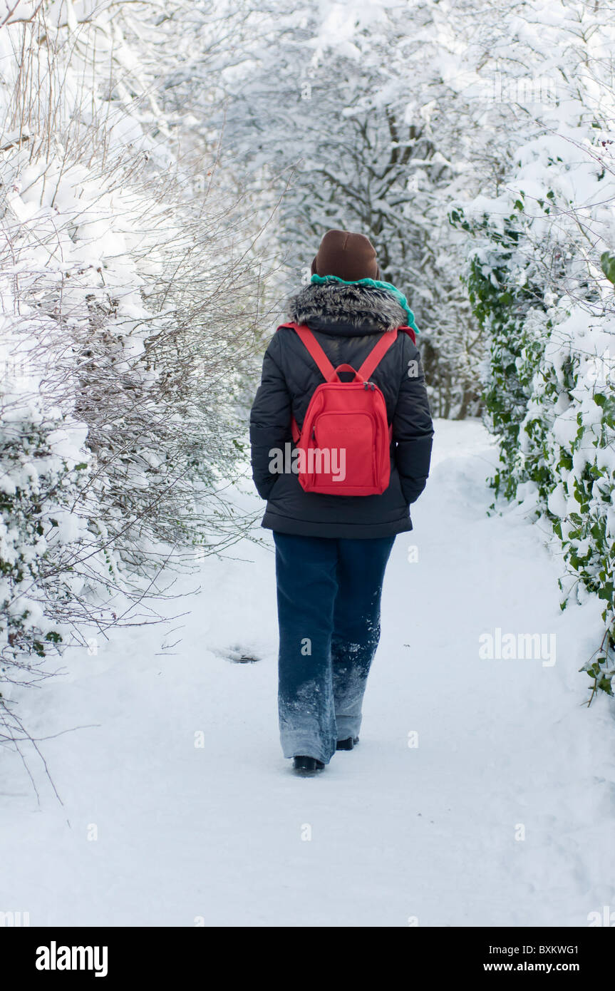 Woman walking along a snow covered path in Redditch, Worcestershire. Stock Photo