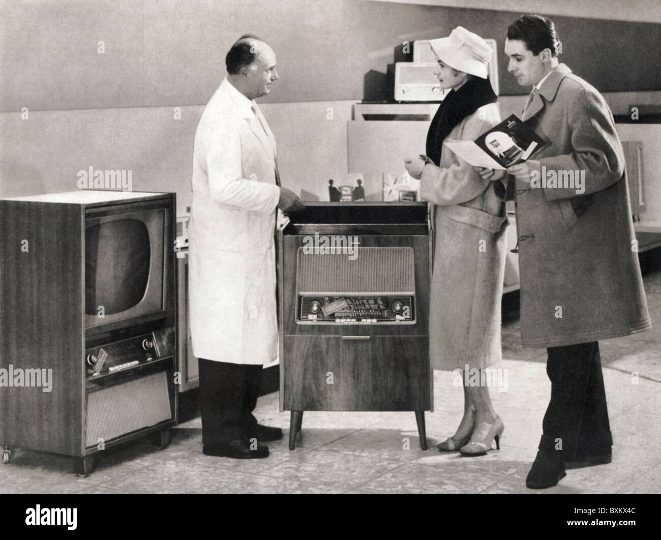 broadcast,radio,radio and television shop,sale of a music chest,Germany,1957,1950s,50s,20th century,historic,historical,specialized shop assistant,specialized shop assistants,sales talk,married couple gets information abour Siemens Musiktruhe TR 1,TR1,with integrated radio set and record player,television set,TV set,TV,television sets,TV sets,TVs,retail,retail trade,retailing,retail and wholesale,retail,specialized dealer,economic miracle,economic miracles,home electronics,consumer electronics,entertainment electronics,home ent,Additional-Rights-Clearences-Not Available Stock Photo