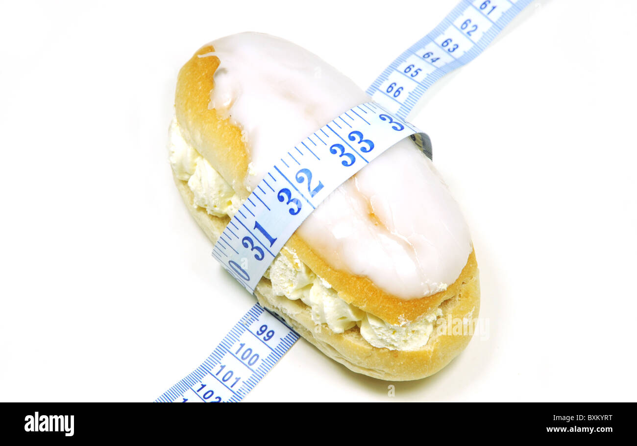 High key concept dieting image of a cream cake with a tape measure wrapped around it Stock Photo
