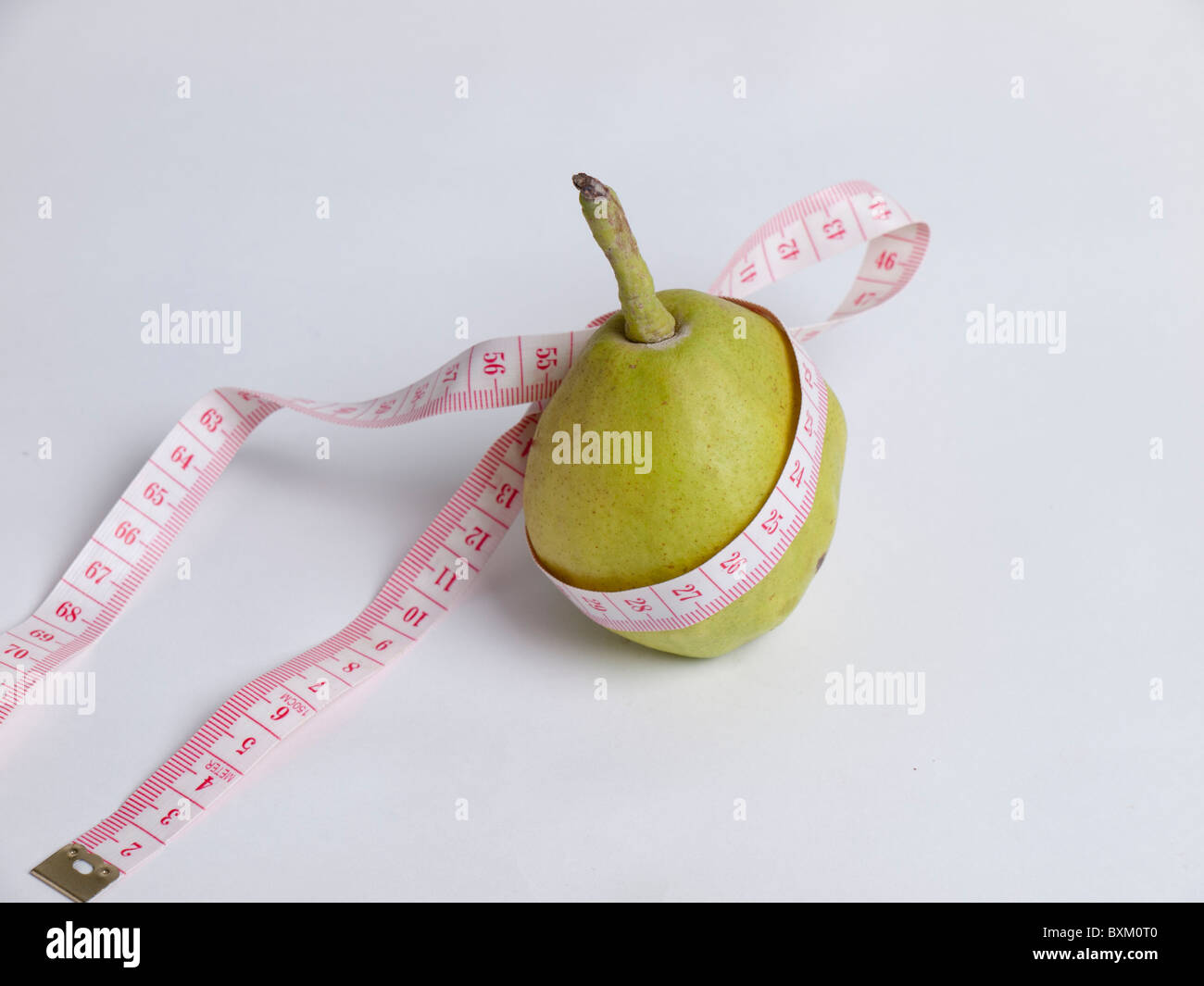Ripe green pear with measuring tape, A diet consisting of fruits can aid in weight loss. Stock Photo