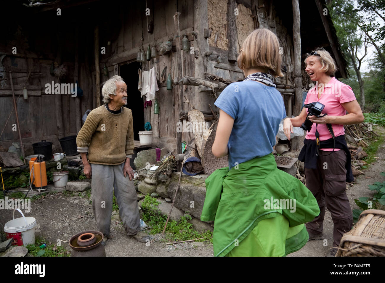 Western tourists interacting with an old Chinese man in a remote village in west China. Stock Photo