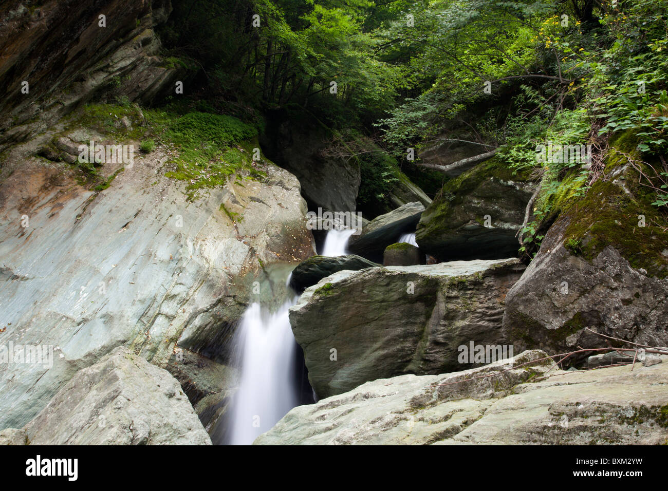 A waterfall tumbles and meanders among boulders in deep gorges in the Min Mountains in Sichuan in China. Stock Photo