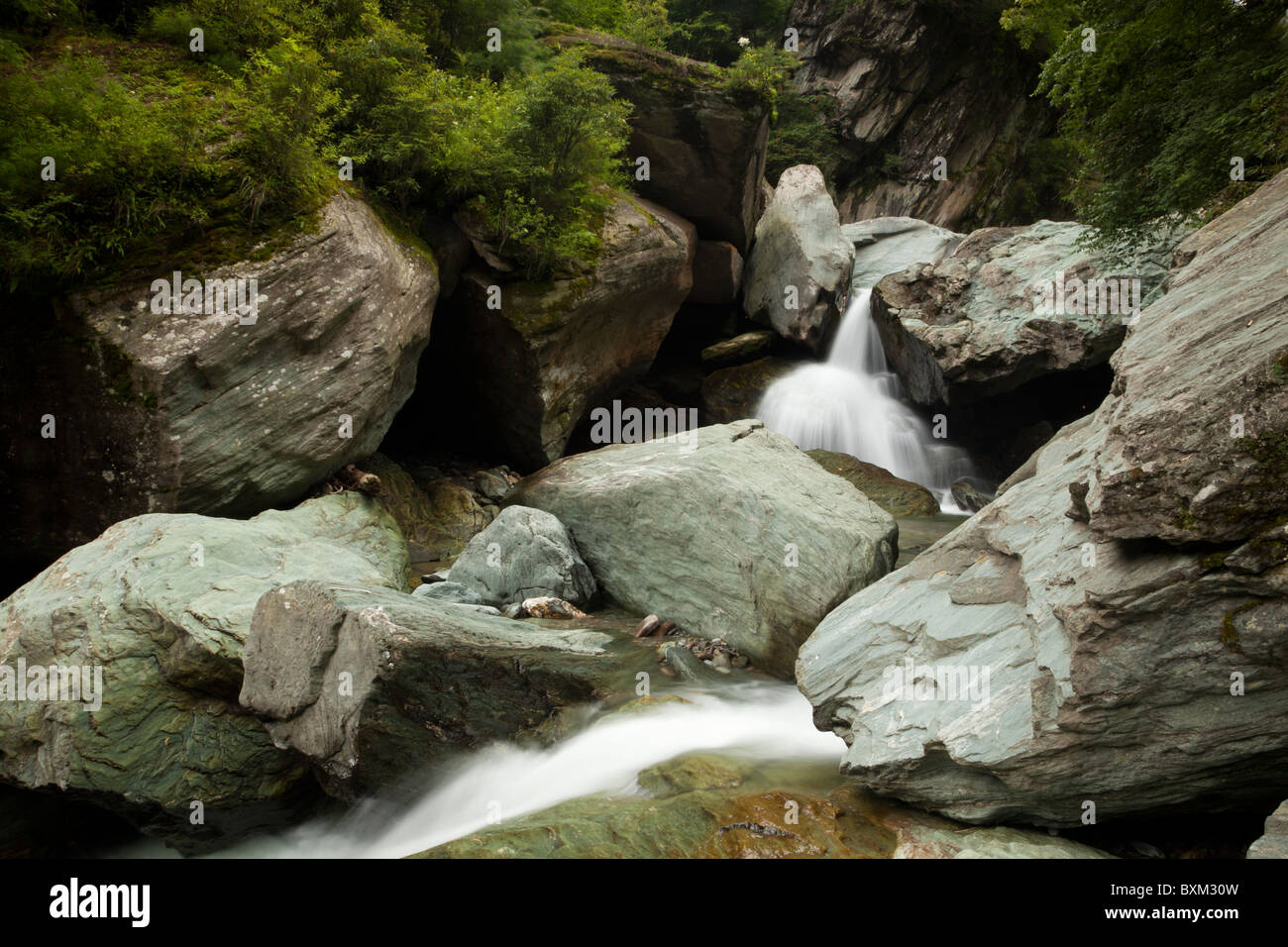 A waterfall tumbles and meanders among boulders in deep gorges in the Min Mountains in Sichuan in China. Stock Photo