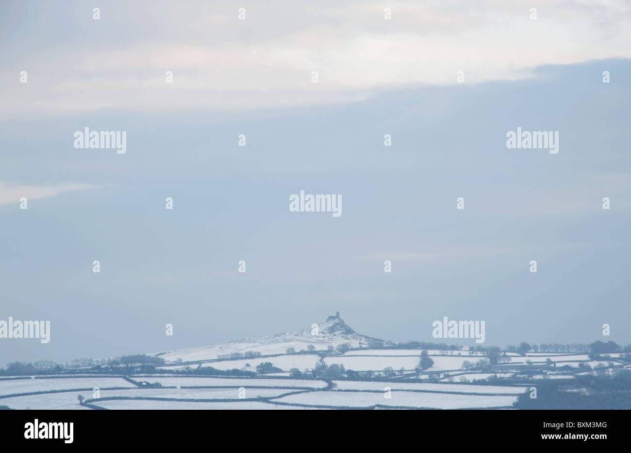 Winter landscape over snow-covered fields, with the church on Brentor rising from the horizon Stock Photo