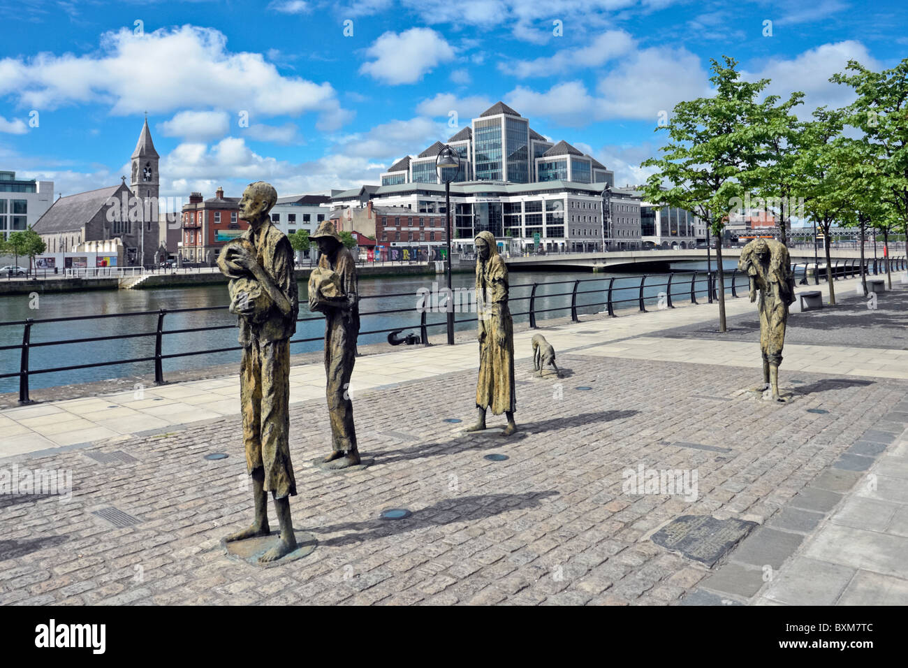 The Famine Memorial on Custom House Quay on the River Liffey in Dublin Ireland with One Georges Quay Plaza across the river. Stock Photo