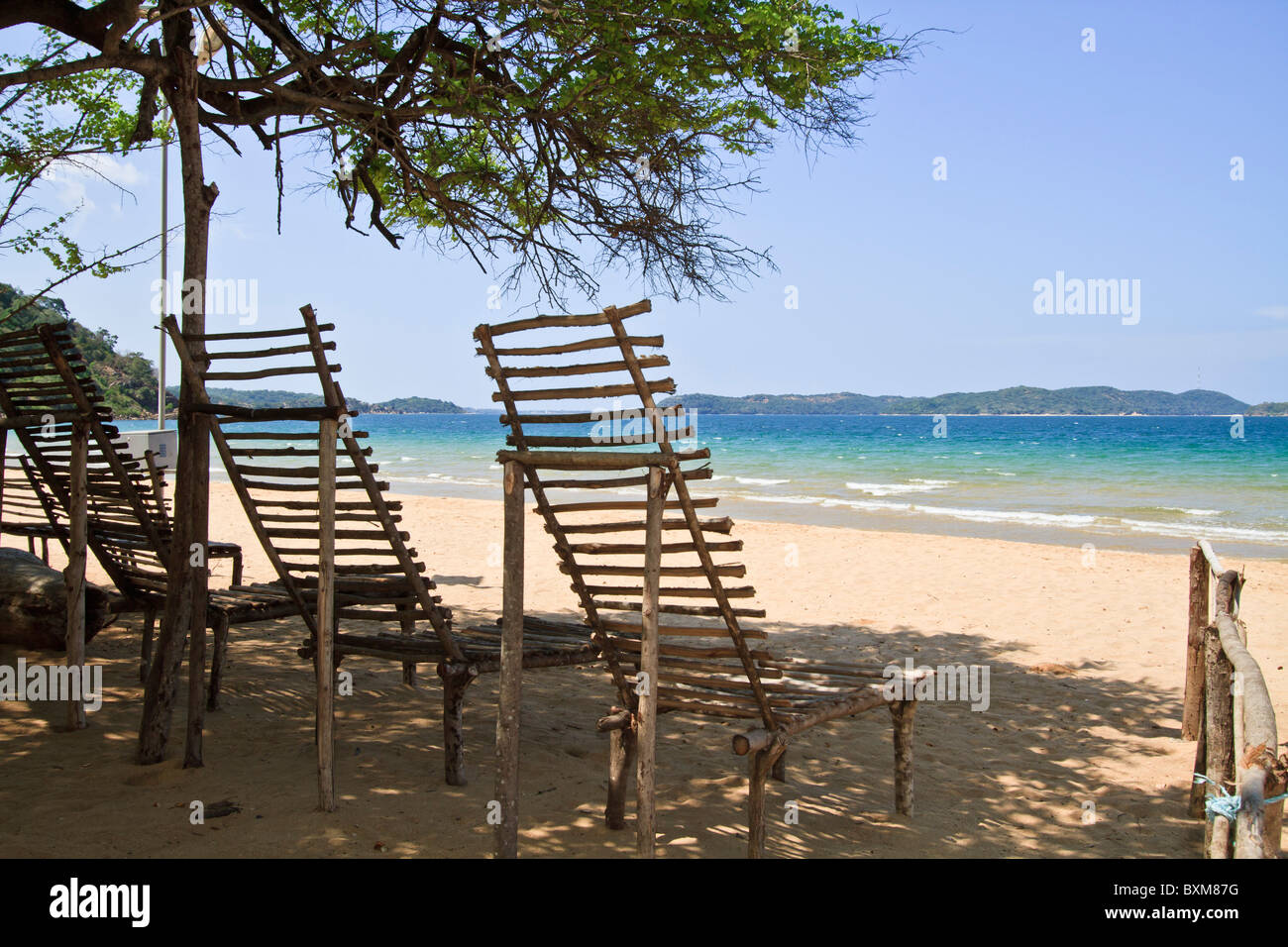 Rustic wooden beach loungers on a tropical beach at Marble Beach, Trincomalee, Sri Lanka East Coast. Stock Photo