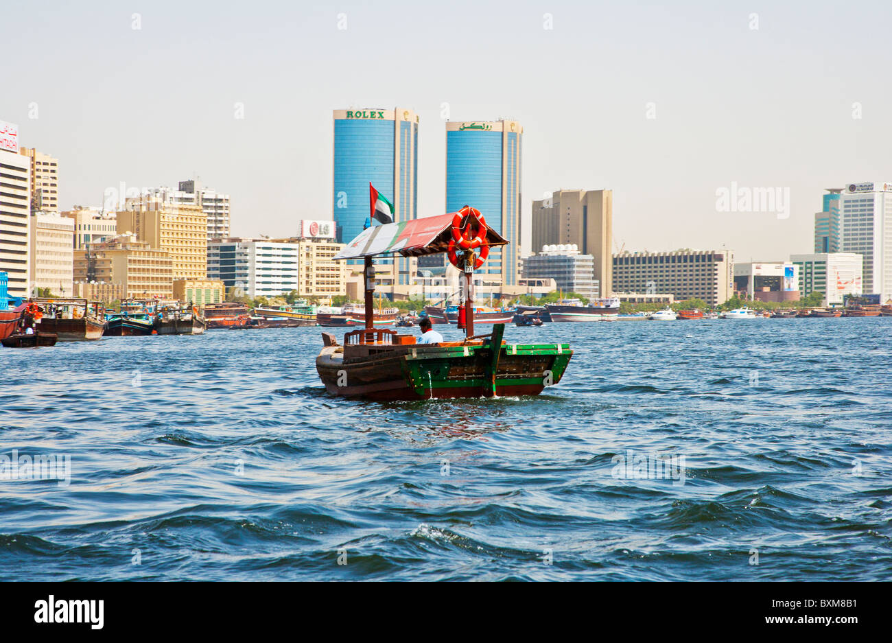 Traditional Arabian boat, abra or dhow moored in the Dubai Creek, Old Dubai, UAE, against a backdrop of modern buildings. Stock Photo